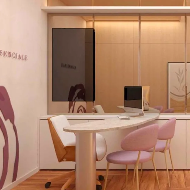 Recepção da Essenciale, com o logo na parede, mesa de mármore e cadeiras rosadas